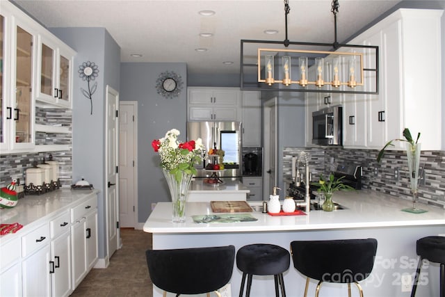 kitchen featuring pendant lighting, white cabinetry, stainless steel appliances, and a kitchen breakfast bar