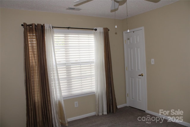 empty room with a healthy amount of sunlight, a textured ceiling, and ceiling fan