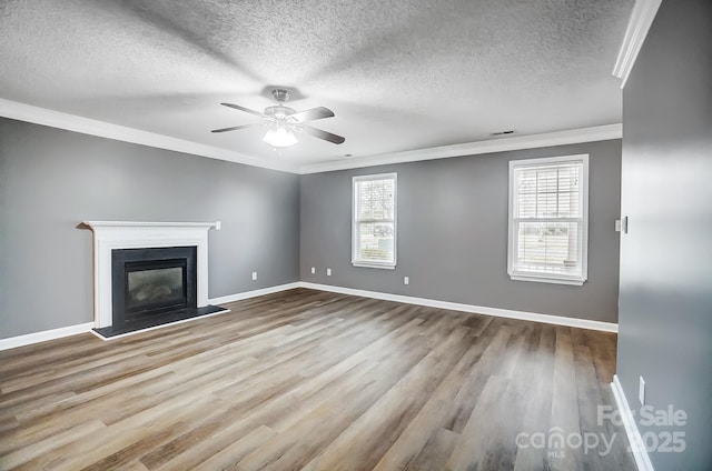 unfurnished living room featuring a textured ceiling, a healthy amount of sunlight, light wood-type flooring, and ornamental molding