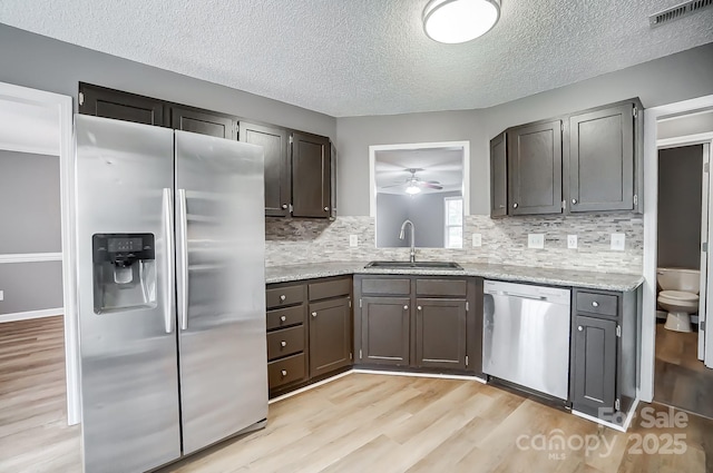 kitchen with sink, ceiling fan, a textured ceiling, tasteful backsplash, and stainless steel appliances