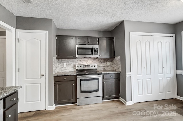 kitchen featuring backsplash, light stone countertops, a textured ceiling, appliances with stainless steel finishes, and dark brown cabinetry