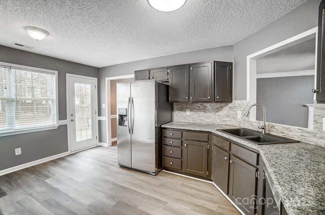 kitchen with sink, decorative backsplash, stainless steel fridge, a textured ceiling, and light hardwood / wood-style floors