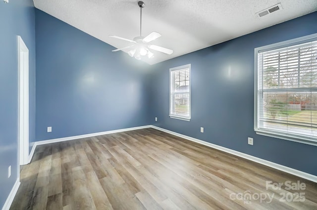 empty room featuring ceiling fan, light wood-type flooring, and a textured ceiling