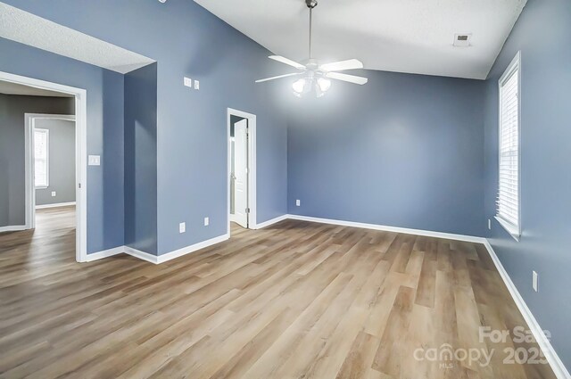 empty room featuring a textured ceiling, light hardwood / wood-style flooring, ceiling fan, and lofted ceiling