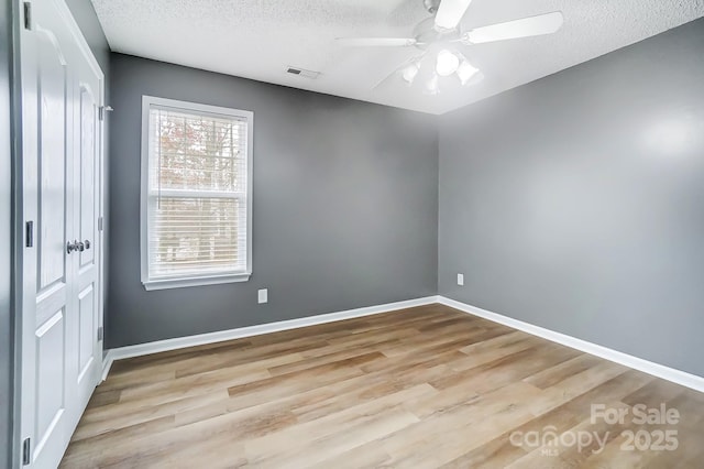 empty room with ceiling fan, light hardwood / wood-style flooring, and a textured ceiling