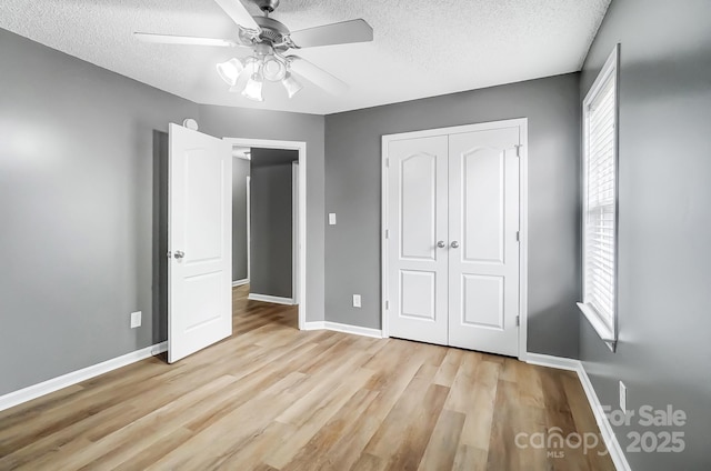 unfurnished bedroom featuring ceiling fan, light hardwood / wood-style floors, a textured ceiling, and a closet