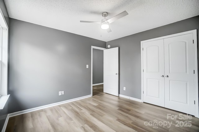 unfurnished bedroom with light wood-type flooring, a textured ceiling, a closet, and ceiling fan