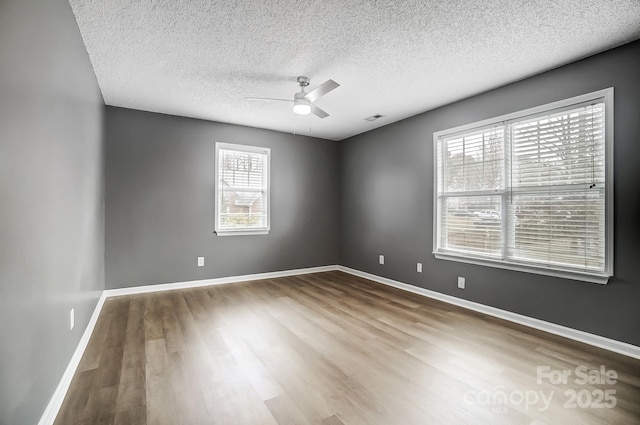 spare room featuring ceiling fan, wood-type flooring, and a textured ceiling