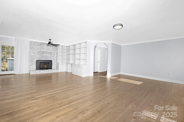 unfurnished living room featuring light hardwood / wood-style floors, a brick fireplace, ceiling fan, and crown molding