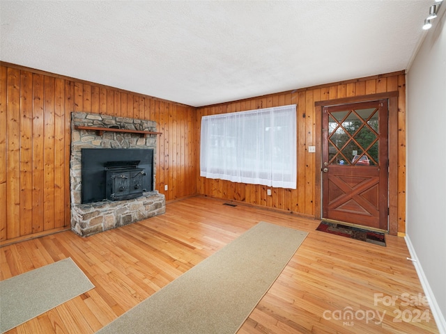 unfurnished living room with wood walls, hardwood / wood-style floors, and a textured ceiling