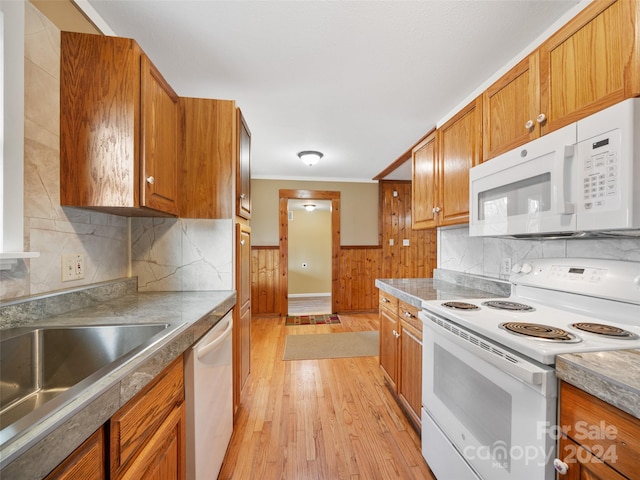 kitchen with tasteful backsplash, ornamental molding, white appliances, sink, and light hardwood / wood-style floors