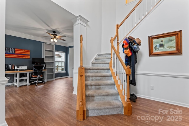 stairway with built in shelves, decorative columns, ceiling fan, and crown molding