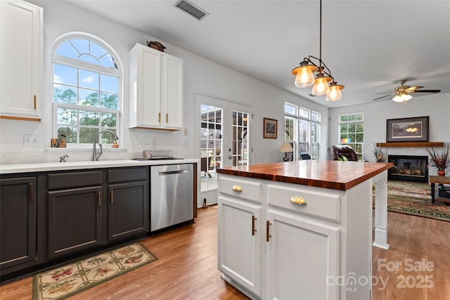 kitchen with french doors, stainless steel dishwasher, white cabinets, a kitchen island, and hanging light fixtures