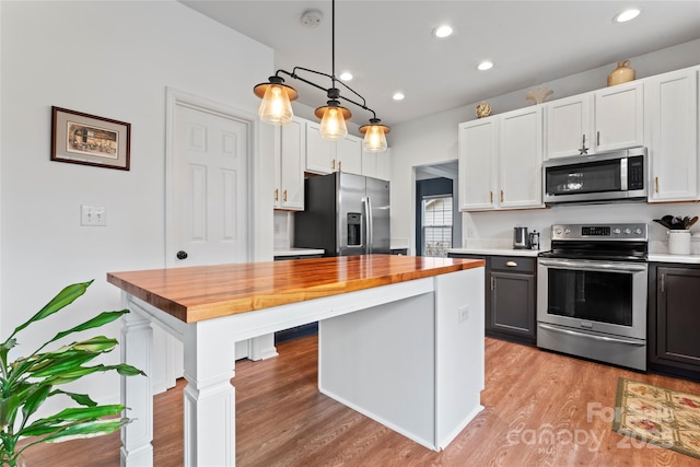 kitchen featuring wood counters, white cabinets, decorative light fixtures, light hardwood / wood-style floors, and stainless steel appliances