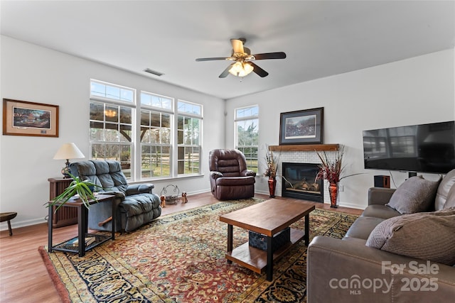 living room with ceiling fan, a fireplace, and wood-type flooring