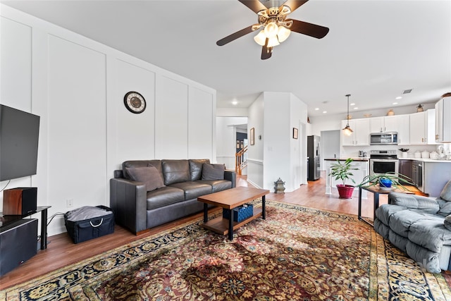 living room with light wood-type flooring, ceiling fan, and sink