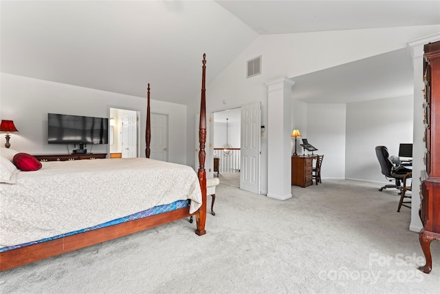 carpeted bedroom with ensuite bath, ornate columns, and lofted ceiling