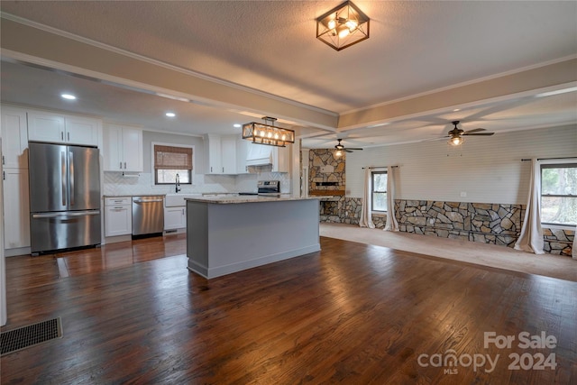 kitchen with a center island, dark wood-type flooring, white cabinets, hanging light fixtures, and appliances with stainless steel finishes