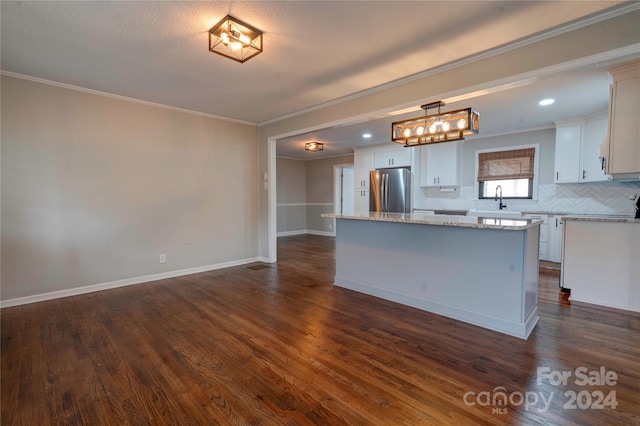 kitchen with stainless steel refrigerator, white cabinetry, hanging light fixtures, dark wood-type flooring, and a kitchen island