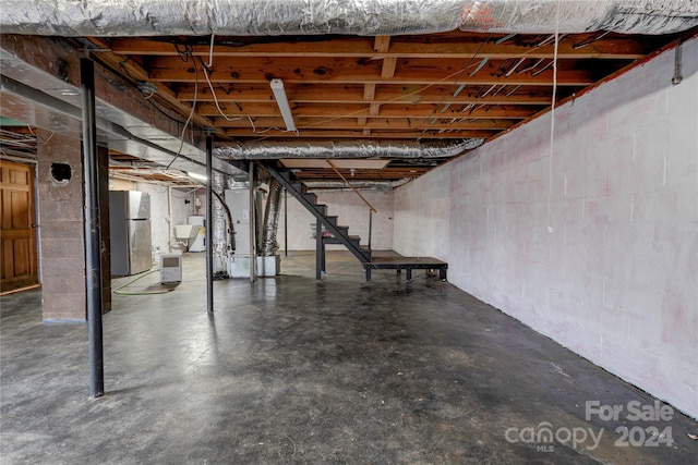 basement featuring stainless steel refrigerator and heating unit