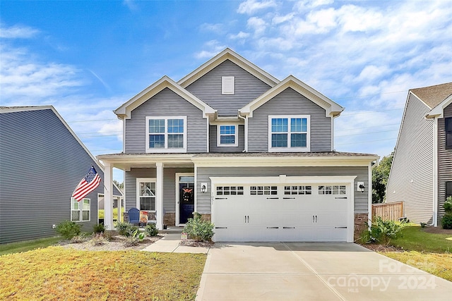 craftsman inspired home with a garage and a front lawn