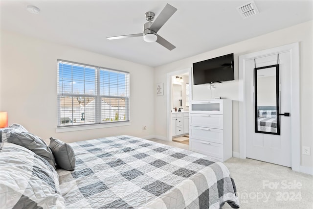 bedroom featuring ceiling fan, light colored carpet, and ensuite bathroom