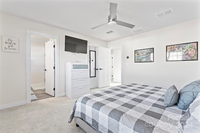 bedroom featuring ceiling fan, light colored carpet, and ensuite bath