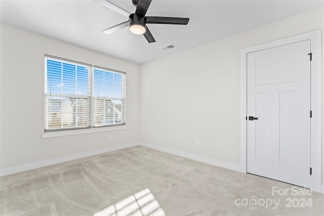 empty room featuring ceiling fan and light colored carpet