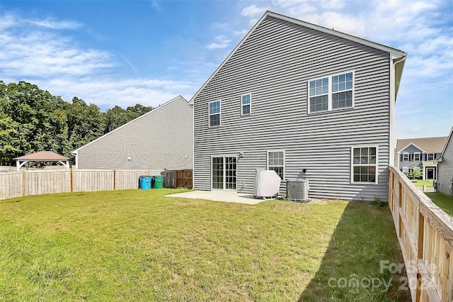 rear view of property with a lawn, a patio, and central AC