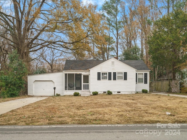 view of front of home with a garage, a front lawn, and a sunroom