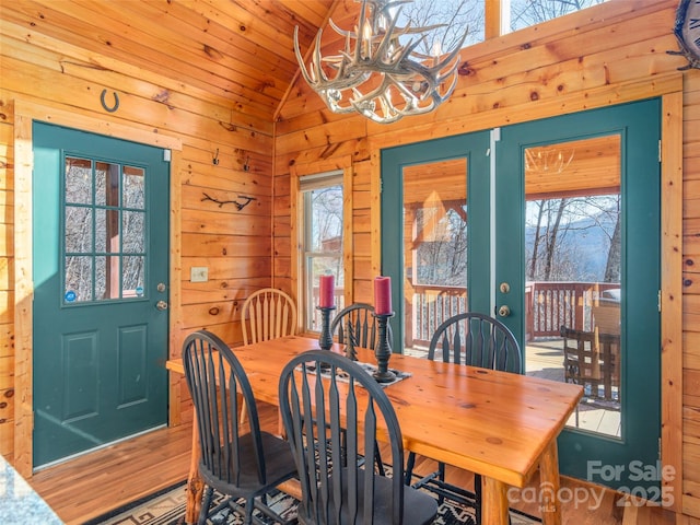 dining area featuring a notable chandelier, wood walls, wood ceiling, and vaulted ceiling