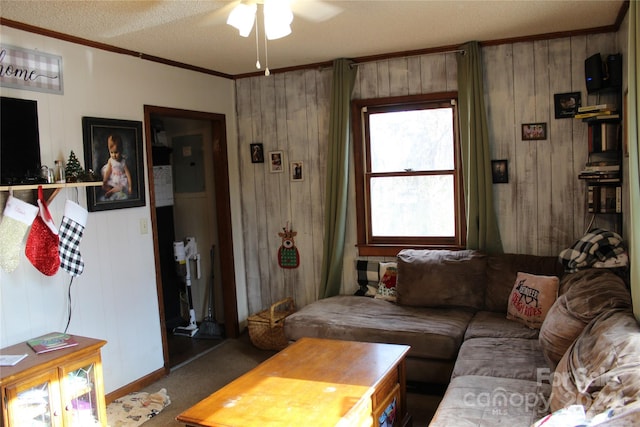 living room featuring a textured ceiling, ceiling fan, crown molding, carpet floors, and wood walls