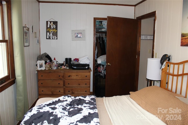 bedroom with wooden walls, a closet, and ornamental molding