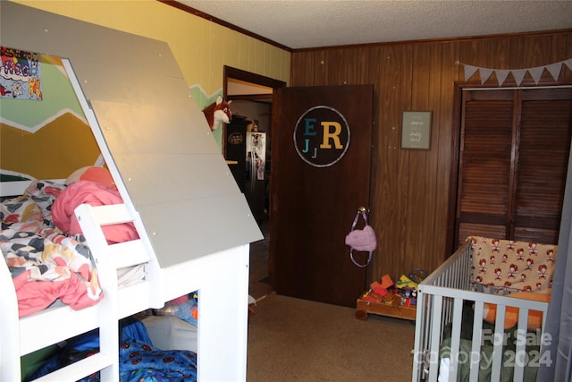 bedroom featuring crown molding, wood walls, carpet floors, black refrigerator, and a nursery area