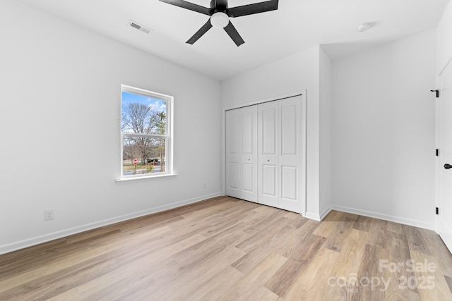 unfurnished bedroom featuring visible vents, baseboards, light wood-style floors, and a closet