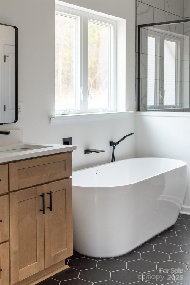 full bath with a freestanding tub, vanity, and tile patterned flooring