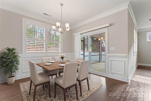 dining space with dark hardwood / wood-style floors, ornamental molding, and an inviting chandelier