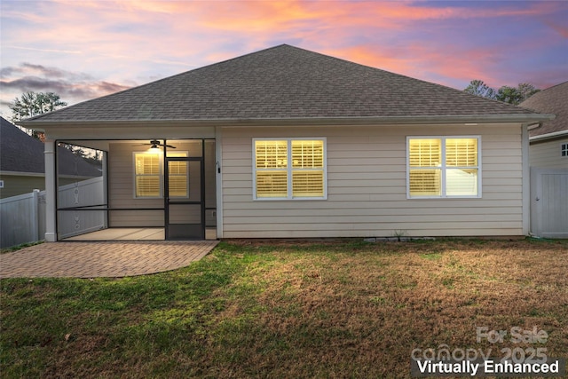 back house at dusk featuring a lawn, a patio area, and ceiling fan