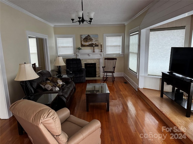 living room with a tile fireplace, crown molding, hardwood / wood-style floors, a chandelier, and a textured ceiling