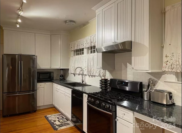 kitchen with light wood-type flooring, sink, black appliances, dark stone countertops, and white cabinets