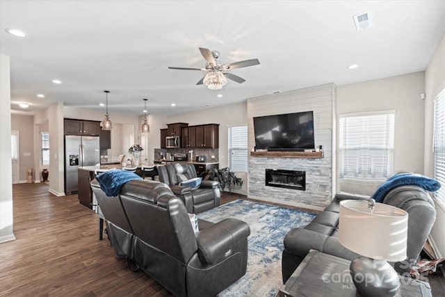 living room featuring a fireplace, dark wood-type flooring, and ceiling fan