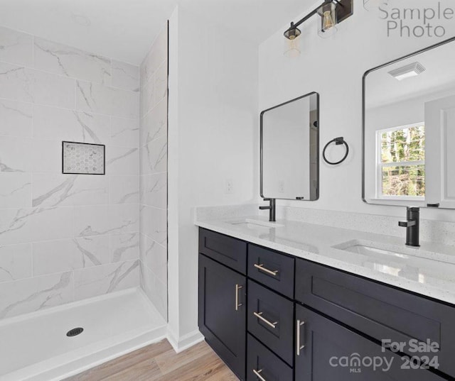 bathroom with tiled shower, vanity, and hardwood / wood-style flooring