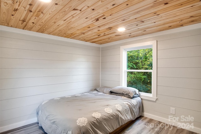 bedroom with hardwood / wood-style flooring, wooden ceiling, and wood walls