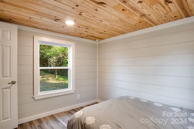 unfurnished bedroom featuring wooden walls, wooden ceiling, and light wood-type flooring