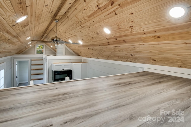 additional living space with wooden ceiling, wooden walls, vaulted ceiling, ceiling fan, and light wood-type flooring