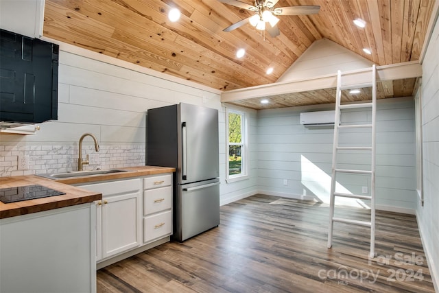 kitchen featuring wood counters, hardwood / wood-style floors, stainless steel fridge, and white cabinetry