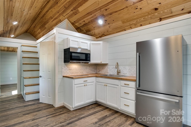 kitchen with butcher block counters, sink, vaulted ceiling, white cabinetry, and stainless steel appliances