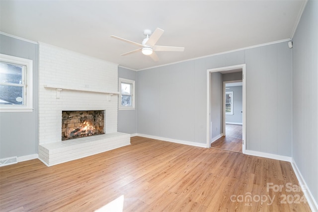 unfurnished living room with a fireplace, wood-type flooring, ceiling fan, and crown molding