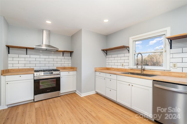 kitchen with white cabinetry, wall chimney exhaust hood, stainless steel appliances, and wood counters