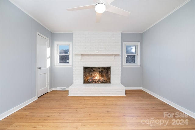 unfurnished living room featuring ceiling fan, light wood-type flooring, ornamental molding, and a fireplace